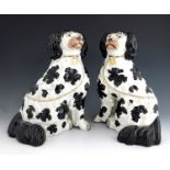 A pair of Staffordshire pottery figures of dogs, circa 1870, modelled as seated black and white span