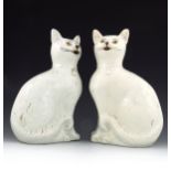A pair of Staffordshire figures of seated cats, circa 1860, wearing collars with small bells, white