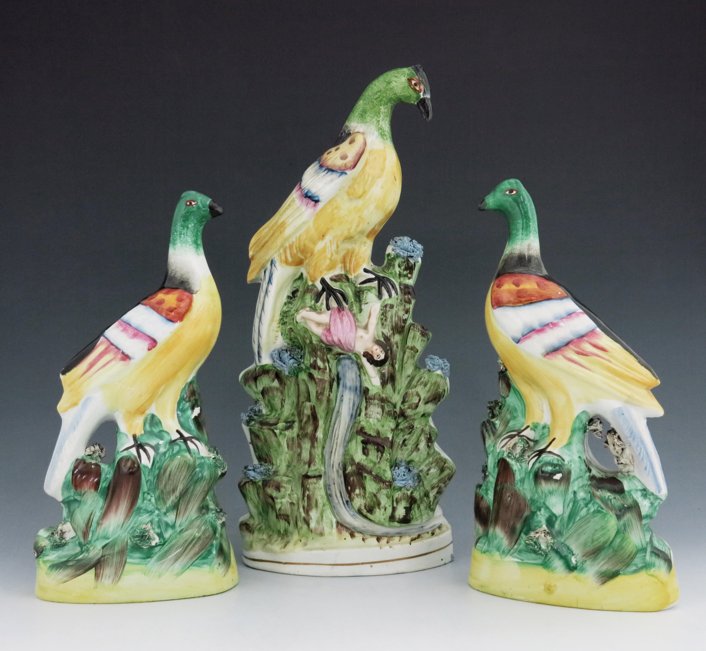 A pair of Staffordshire pottery exotic birds, circa 1850, modelled perched on a green and brown moun