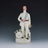 A Staffordshire figure of the 'Duke of Clarence', circa 1891, modelled standing beside a cannon, his