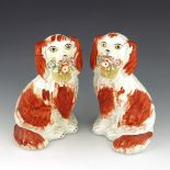 A pair of Staffordshire dog figures, circa 1860, modelled as spaniels holding baskets of flowers in