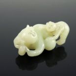 A Chinese pale jade netsuke, in the form of a man and infant playing with a ball, 6cm wide