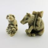 λ Two Japanese ivory netsukes, Meiji period, 1868-1912, each carved as a recumbent dog, one with a