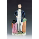 A Staffordshire figure of Dan O'Connell, circa 1850, modelled standing beside a draped column with a