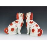 A pair of Staffordshire pottery dogs, circa 1860, modelled as seated King Charles spaniels, iron red