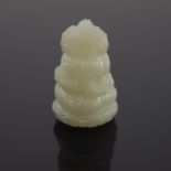 A Chinese pale jade netsuke, carved in the form of a trio of seated buddhas, 3cm high