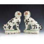 A pair of Staffordshire pottery figures of dogs, circa 1870, smoking pipes, with black painted spots
