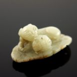A Chinese pale jade netsuke, in the form of a recumbent cat with an insect, mottled brown