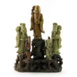 A Chinese soapstone carving, in the form of five robed figures mounted upon a rocky outcrop, 34cm