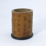 A Chinese bamboo brush pot, the exterior carved with script in relief, 14cm high