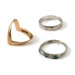 Three white and yellow gold rings, including emerald and diamond five stone, a modernist chevron