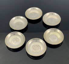 A set of six white metal coin dishes