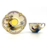 Hadley's Worcester, a cabinet cup and saucer, lobed and painted with a pheasant in open countryside,