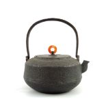A Japanese cast iron spirit teapot, textured surface with loop swing handle, bronze flat cover
