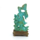 An oriental turquoise figure of a Geisha, modelled standing with a fan beside foliage, 15cm high,
