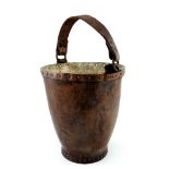 A tan leather fire bucket, 19th Century, strap handle, copper rimmed and studded container with a