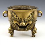 A Chinese gilt bronze censer, fretwork disc cover with coiled dragon, twin ring handles, grinning