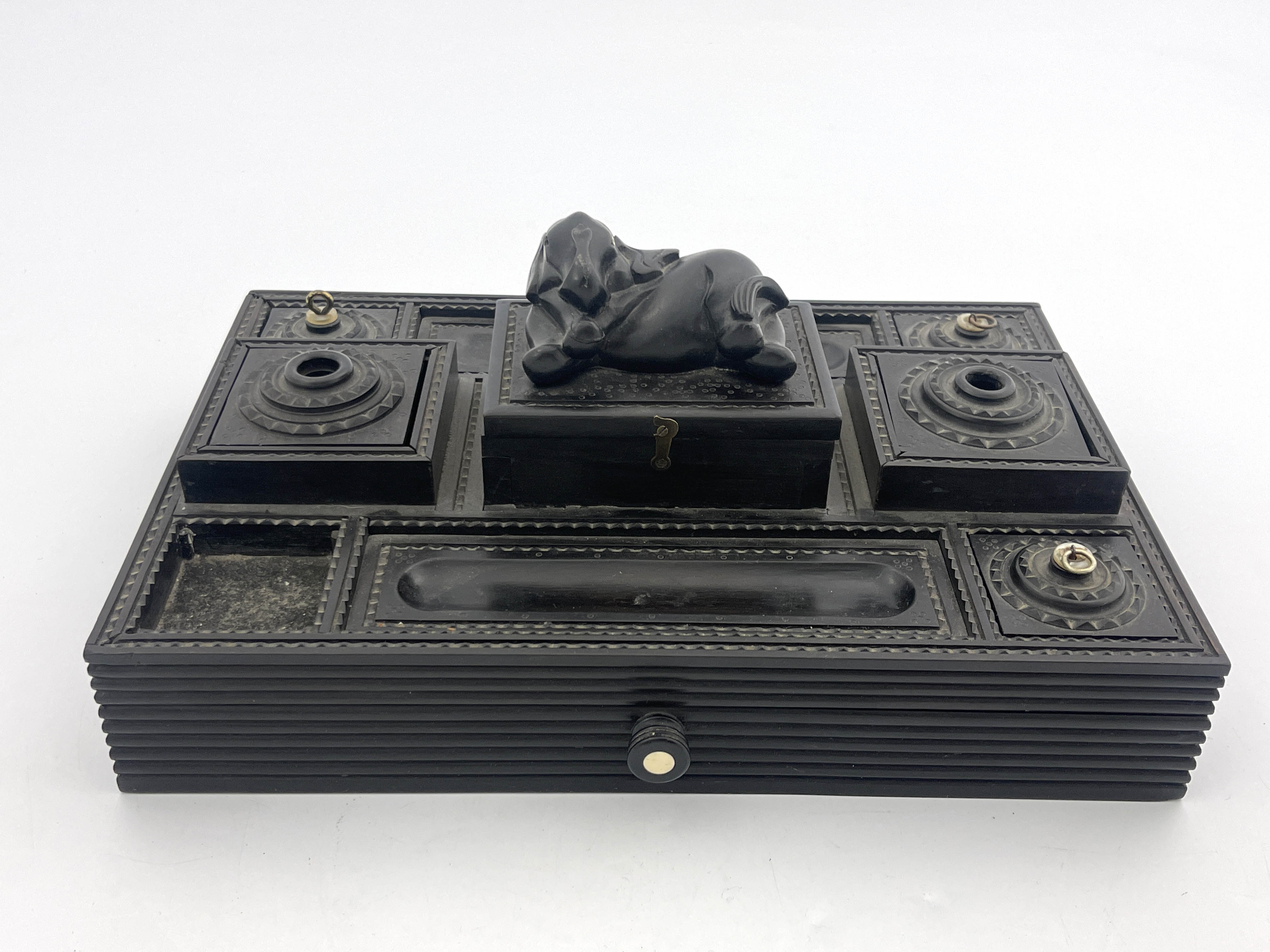 An Anglo-Indian ebony desk stand, late 19th Century, reclining elephant finial, double pen, ink