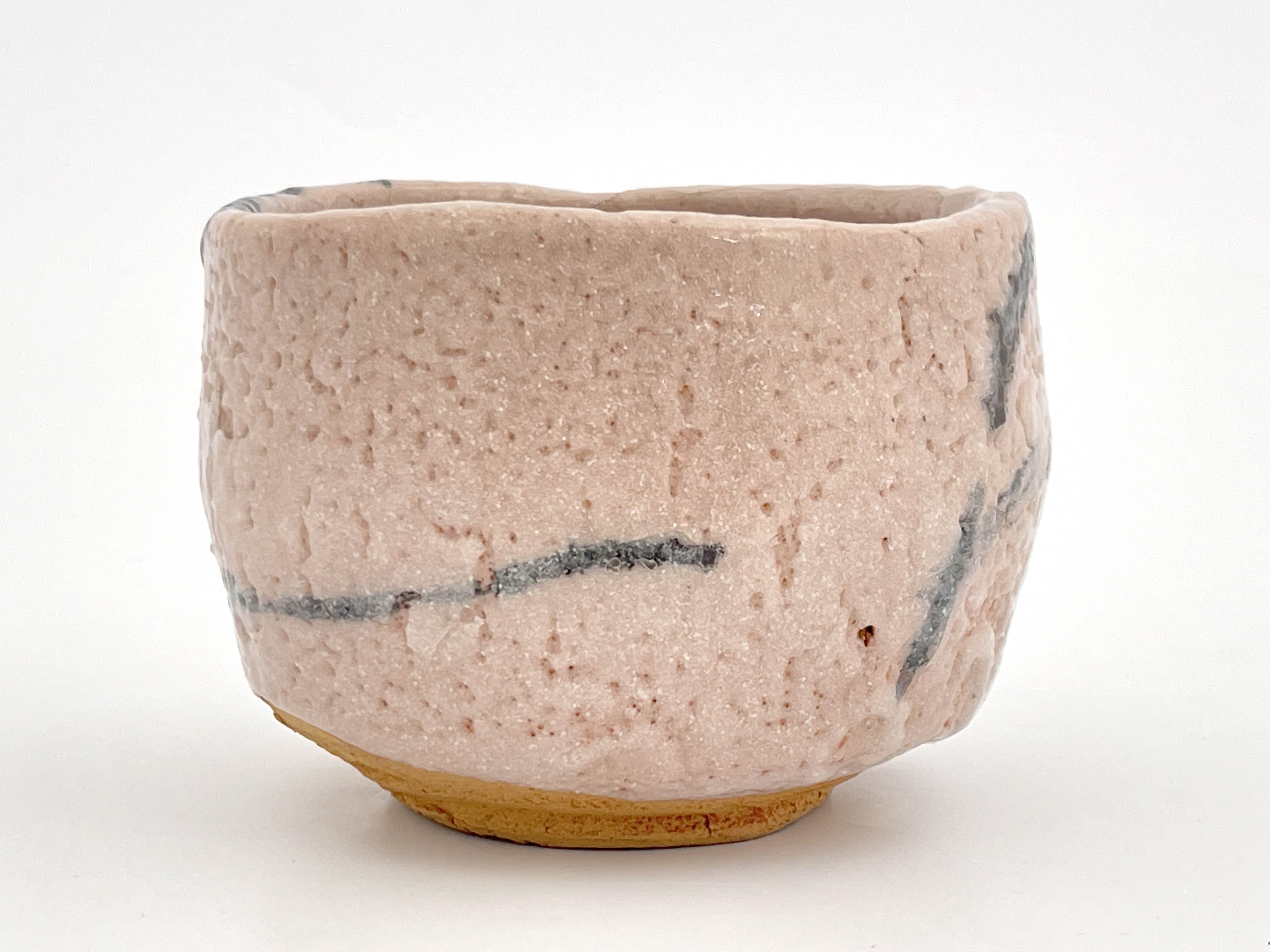 A Japanese Shino ware tea bowl, pitted cream glaze with brush work motifs, incised marks, 12cm wide