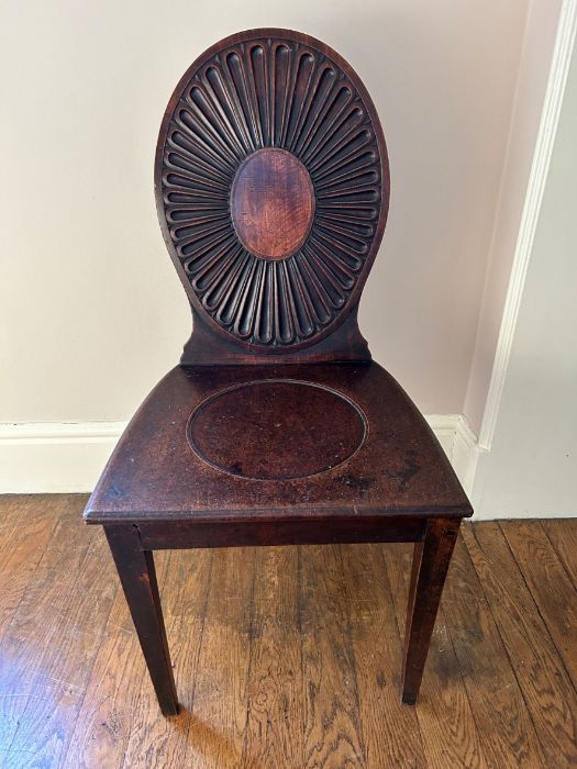 A George III mahogany hall chair after a design by Mayhew and Ince, circa 1770, oval back with