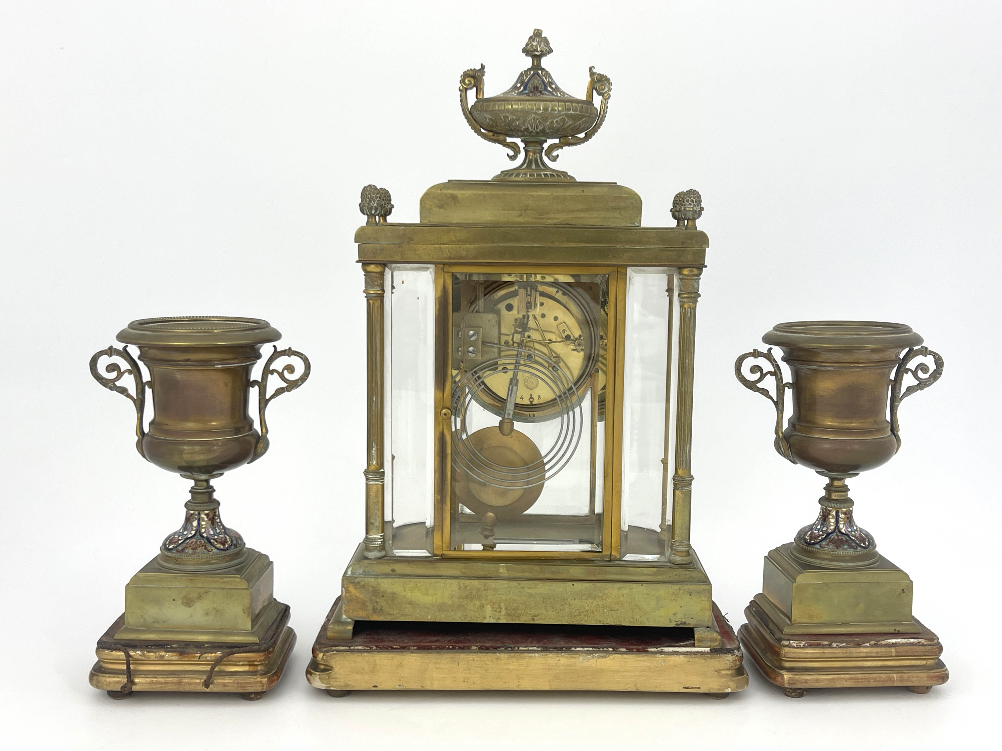 A French brass clock garniture, circa 1870, the breakfront case of Baroque architectural form with