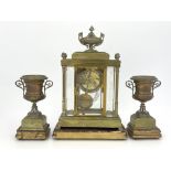 A French brass clock garniture, circa 1870, the breakfront case of Baroque architectural form with