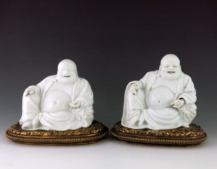 A pair of Chinese blanc de chine Buddhas, 19th Century, the smiling figures seated in repose with