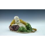 An early 19th Century Chinese porcelain figure of a reclining smiling Buddha, green, yellow and