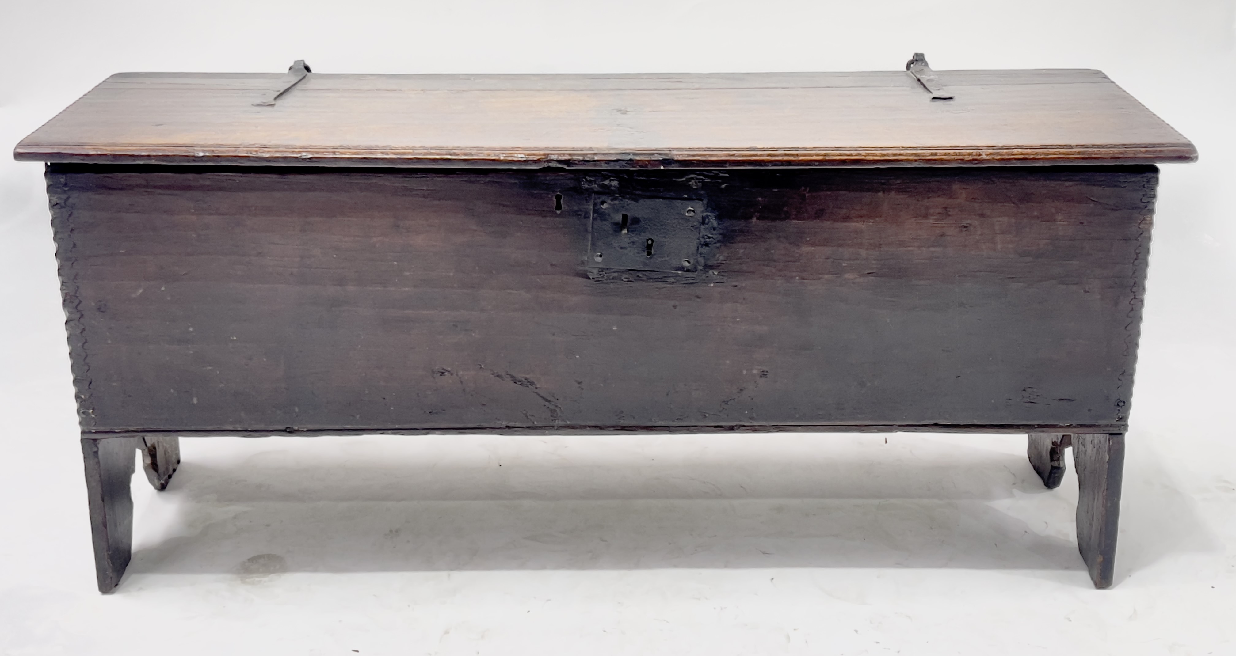 A 17th Century oak plank chest, moulded top with chip carved ends and corners, blacksmith hinges,