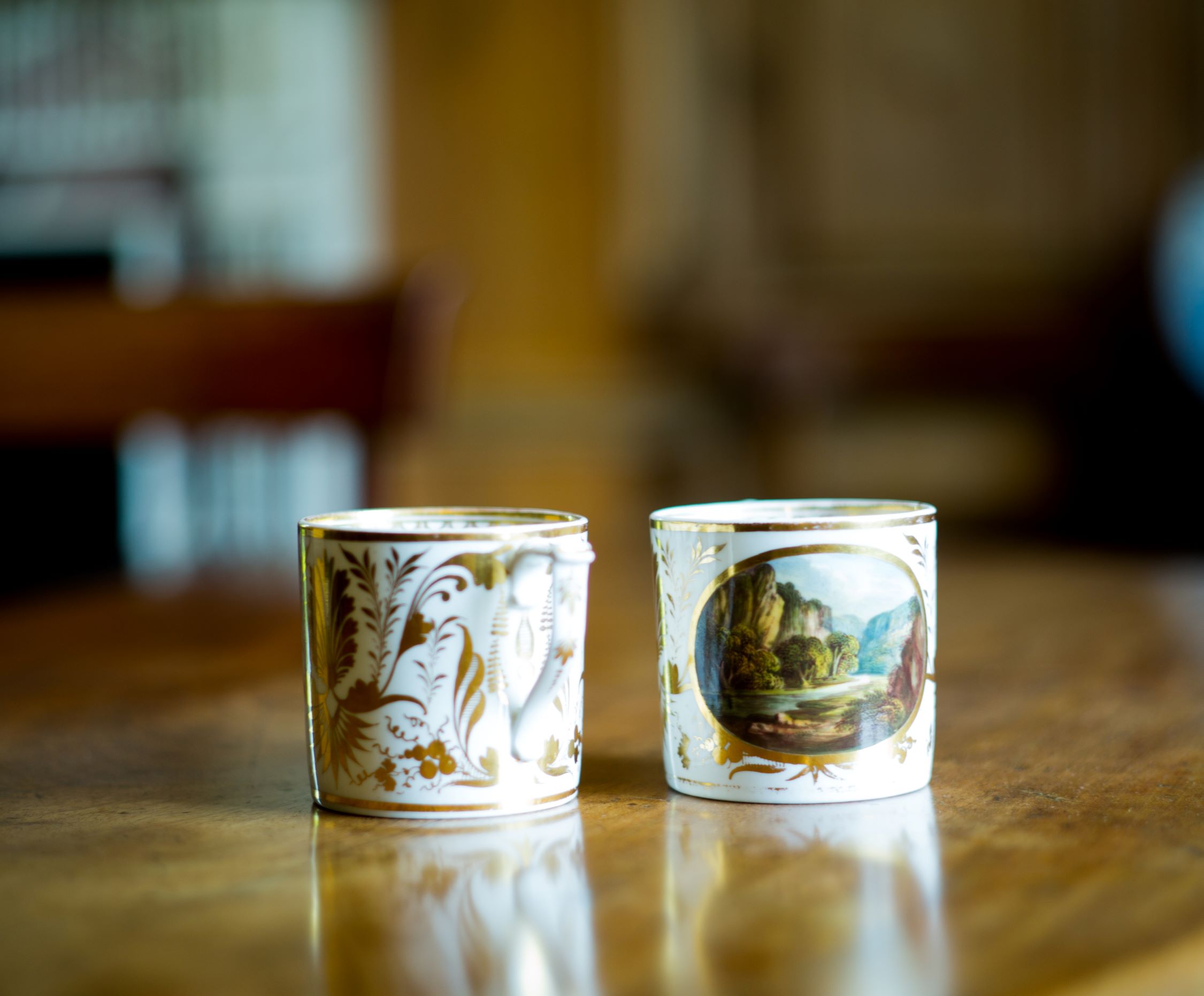 A pair of Derby coffee cans, circa 1810-15, painted with named views, In Dove Dale, Derbyshire and