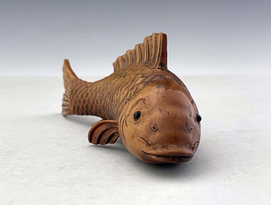 An oriental carved treen model of a fish, realistic fins and gills, glass bead eyes, signed, 16.
