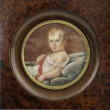 A 19th Century circular portrait miniature of an infant, reclining wearing a red sash, 10cm