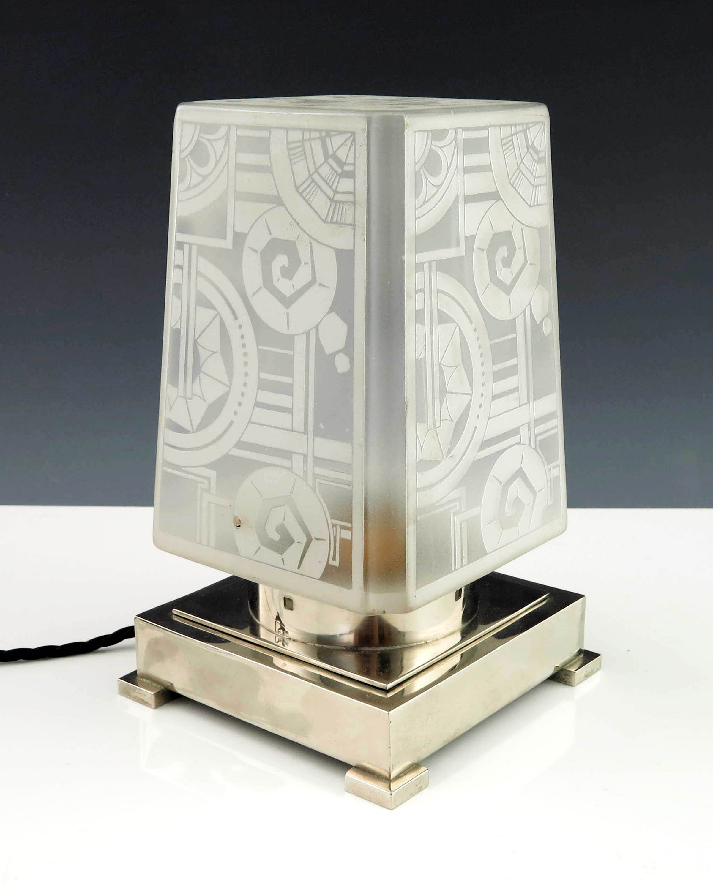 A French Art Deco table lamp with geometric frosted glass shade on chromed circular collar and