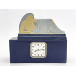 An Art Deco faience clock, circa 1925, cuboid form, the pediment modelled in relief as a reclining