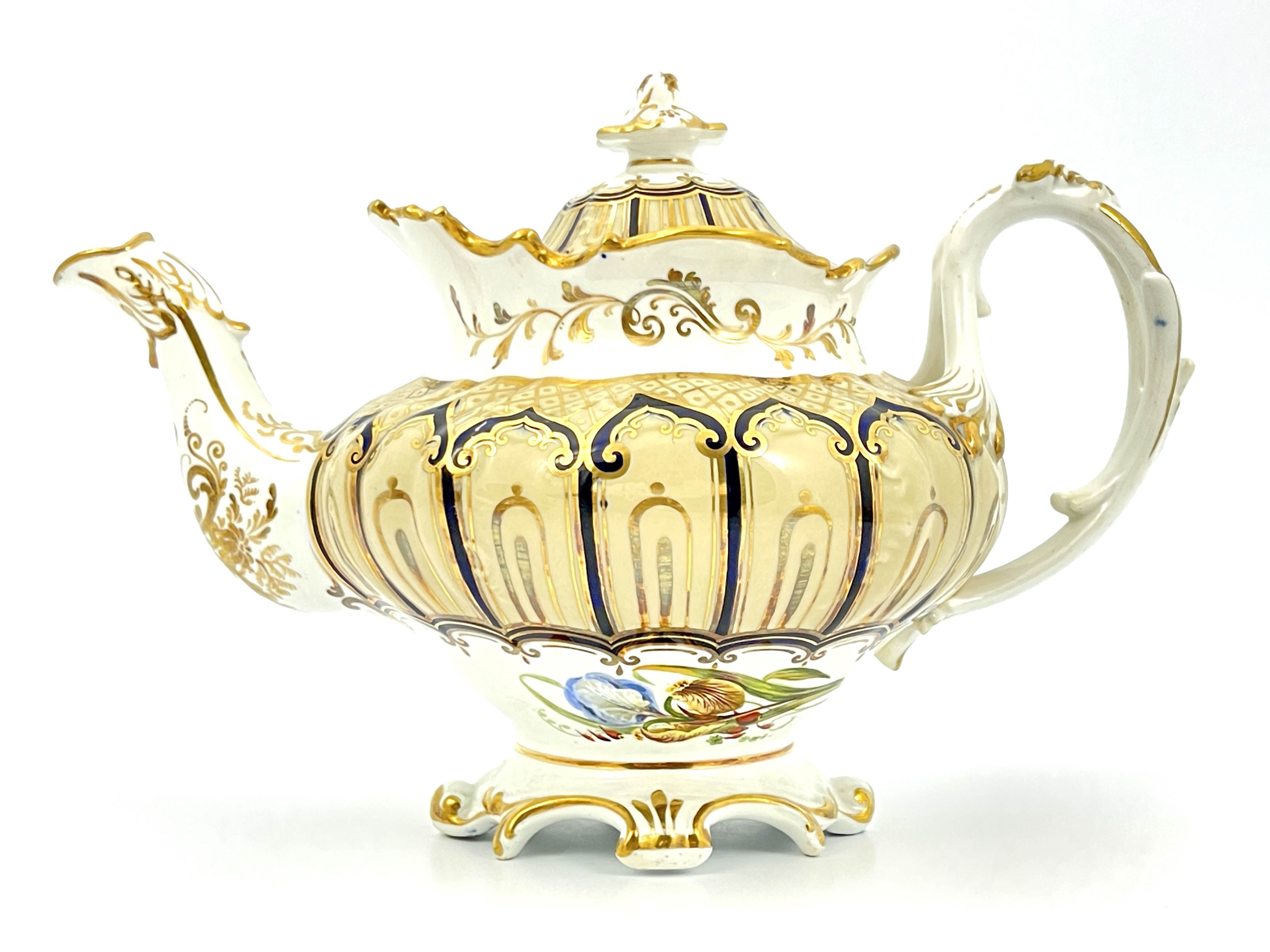 An English bone china teapot and cover, circa 1840, of Rococo design with gilt and blue ogee cover