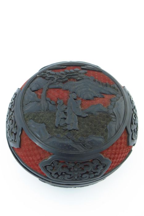 A Chinese red and black lacquer circular covered vessel, carved in high relief with two figures in a - Image 2 of 5