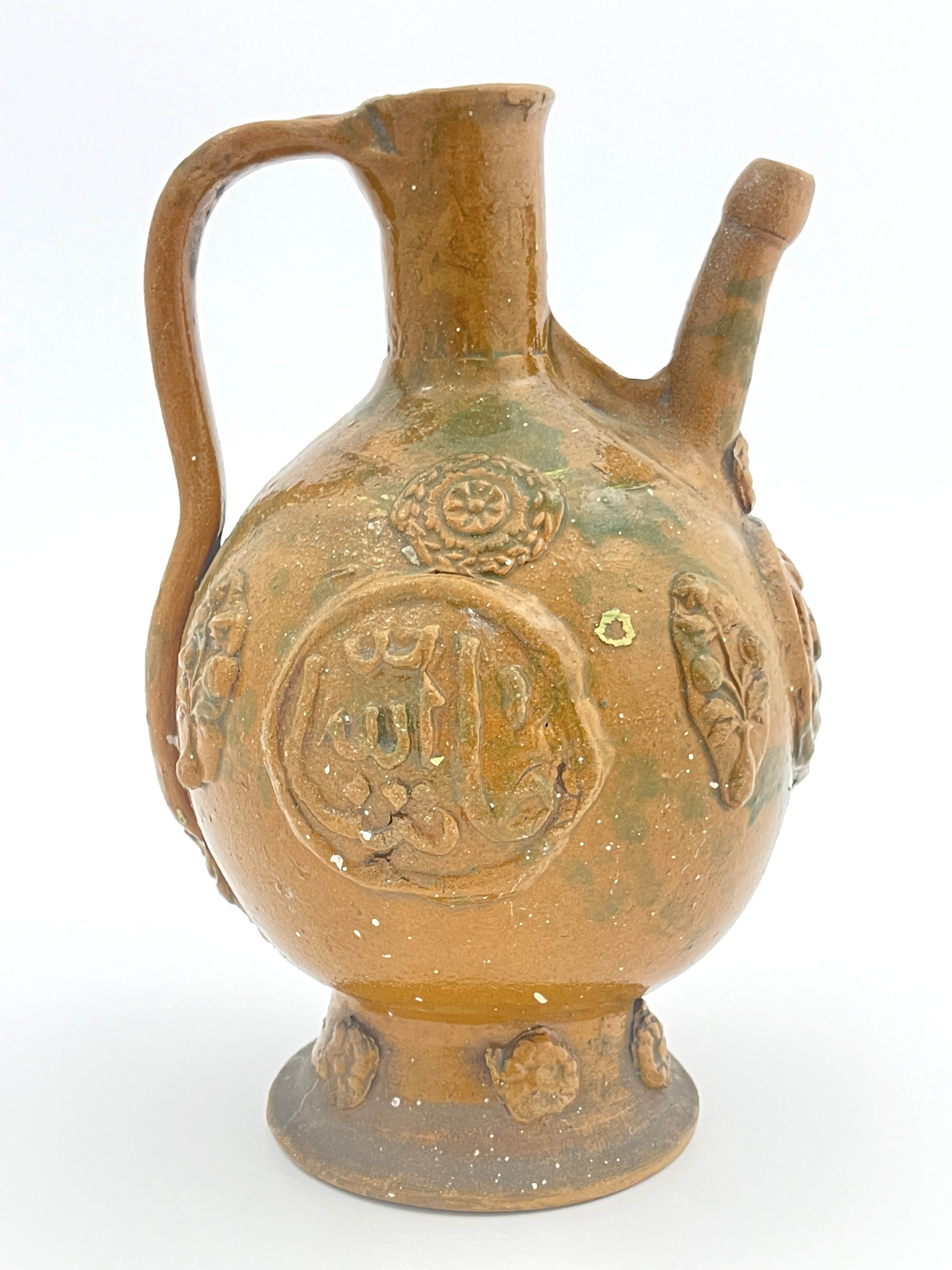 An Islamic stoneware ewer, of ovoid form with handle, sprigged medallions of Islamic script and