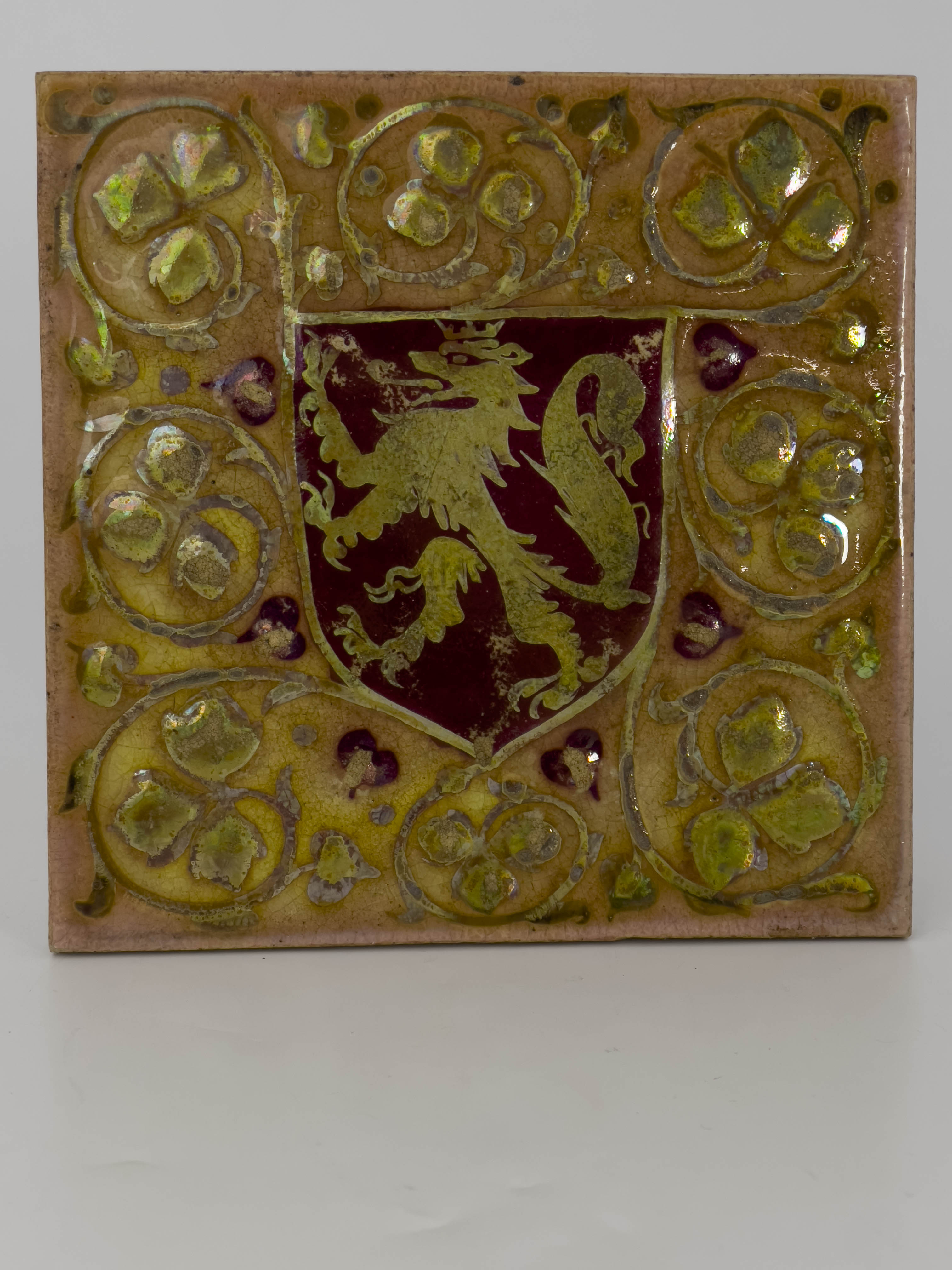 Pilkington, a Royal Lancastrian relief moulded heraldic lustre tile, painted with a red shield