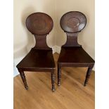 A pair of Regency mahogany hall chairs, circa 1825, waisted backs topped by a dished oval with
