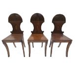 A set of three Regency mahogany hall chairs, circa 1820, waisted backs with oval vacant