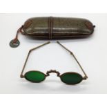 A pair of Chinese folding green lens spectacles with shagreen case with mounted coin
