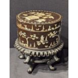 A Chinese circular black lacquered box with mother of pearl inlay, raised on a Chinese hardwood