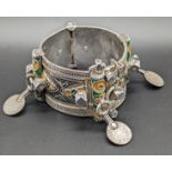 A North African Berber silver tribal bangle with yellow, green and black enameling, mounted with