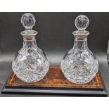 A pair of Mapping and Webb silver collared glass decanters on burr walnut veneered base, with