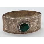 A Liberty & Co. Arts and Crafts silver napkin ring mounted with a green stone, planished finish,