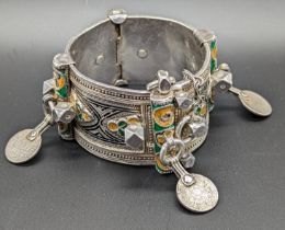 A North African Berber silver tribal bangle with yellow, green and black enameling, mounted with