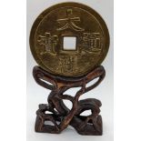 A large Chinese coin on hardwood stand, total item height 20.5cm