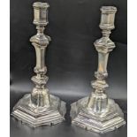 A pair of French 18th century cast silver candlesticks, turned stems with shell decor, marks to