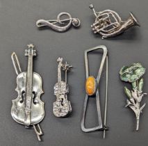 A collection of brooches, mostly musical instruments, violins, some silver