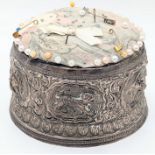 A large Indian silver pin cushion depicting embossed animals to the body, Peacock motif to base,